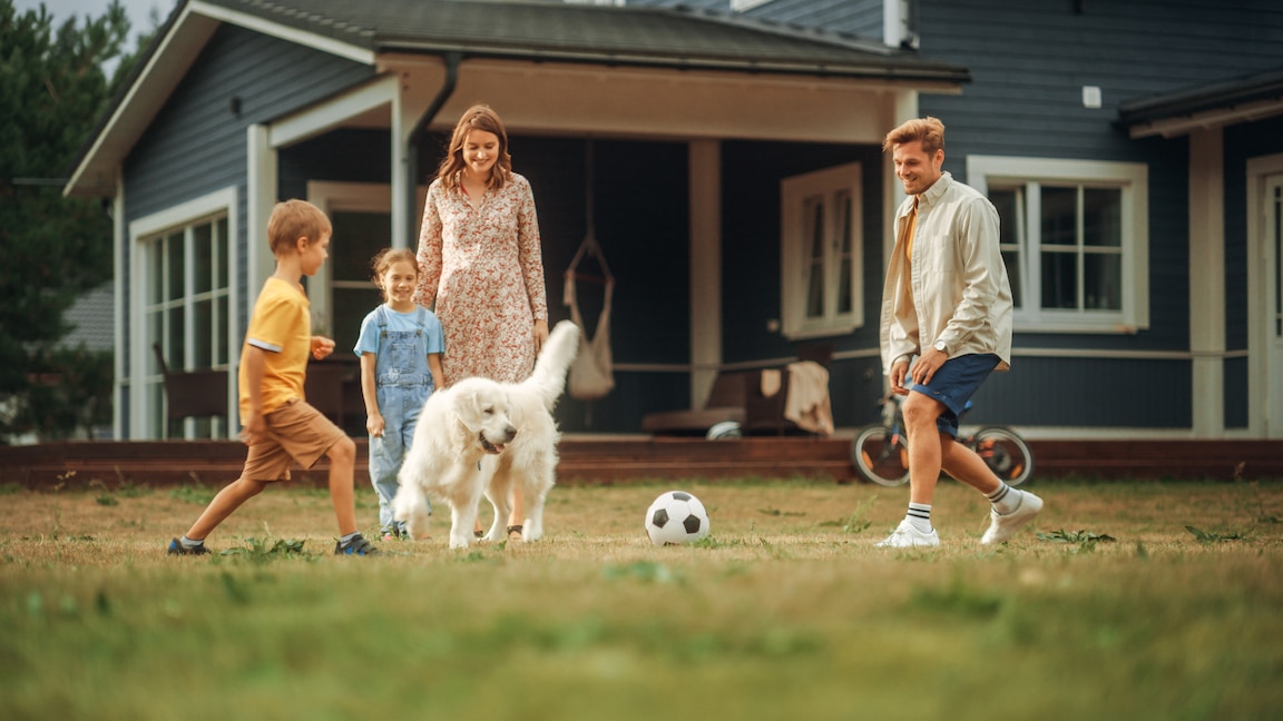 Family playing soccer in front of their insured home