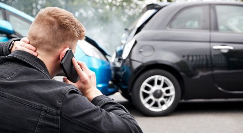 Man on the phone with car accident in the background