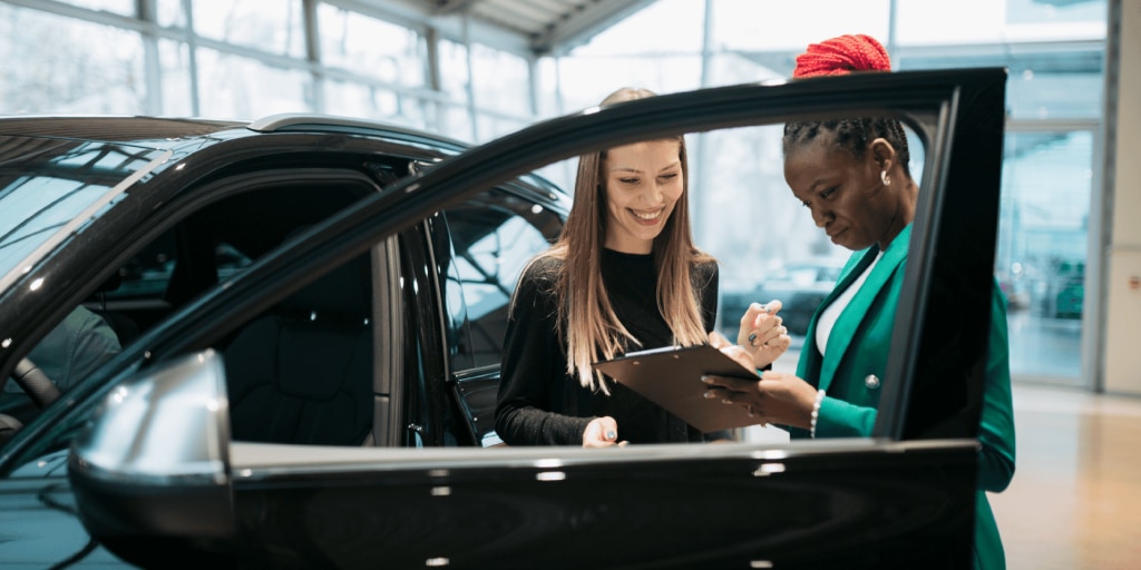 Two women looking at a clipboard at a dealership
