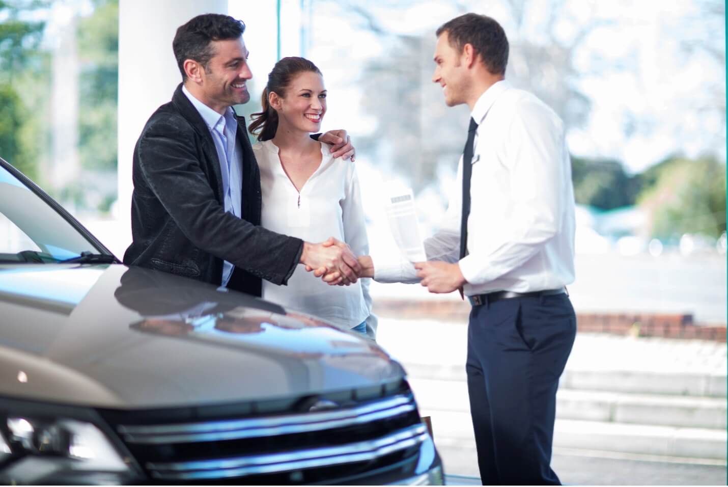 Couple shaking hands with car dealer