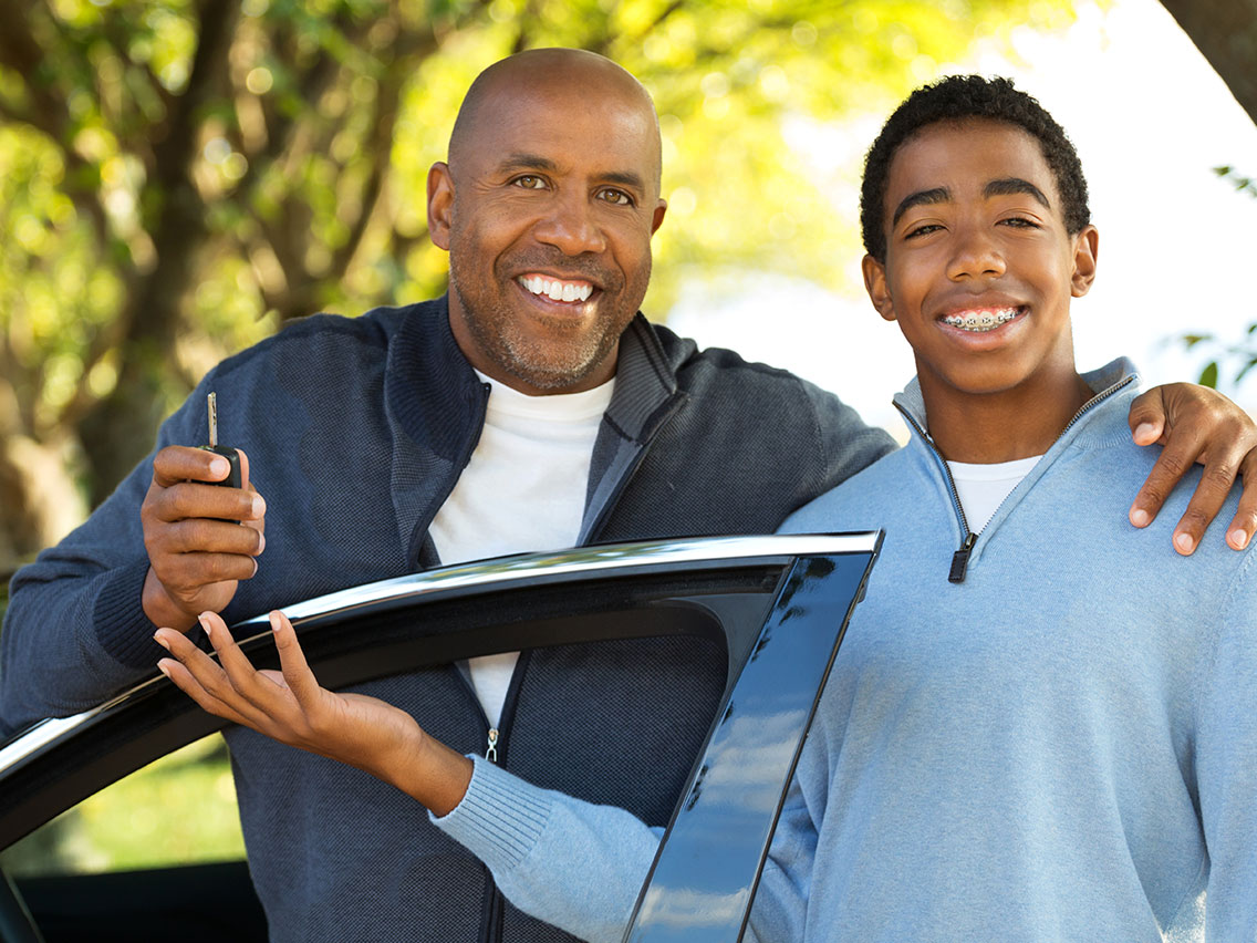 Father handing his teenage son keys to a car
