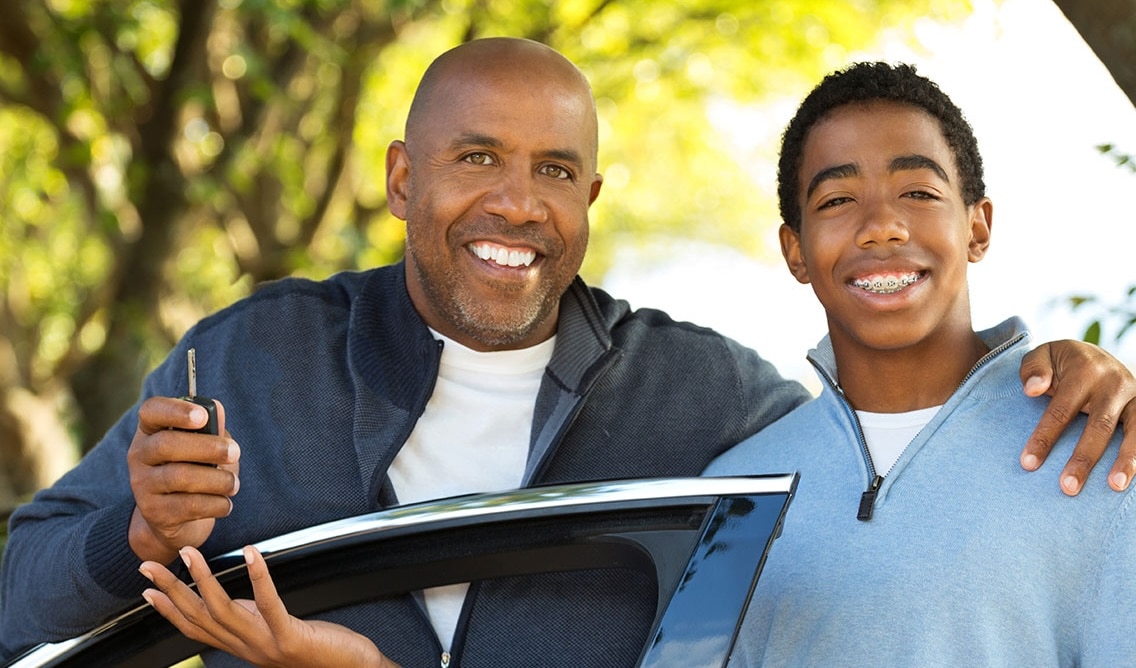 Father handing his teenage son keys to a car
