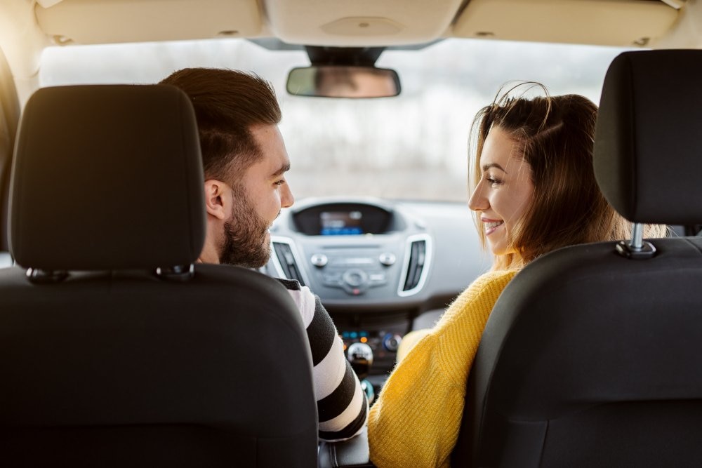 Couple smiling at each other while sitting in a car