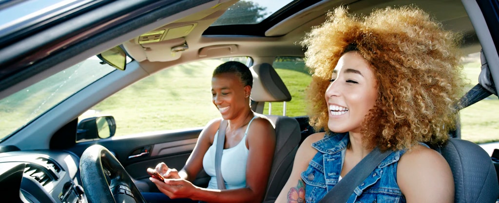 two women riding in a car laughing