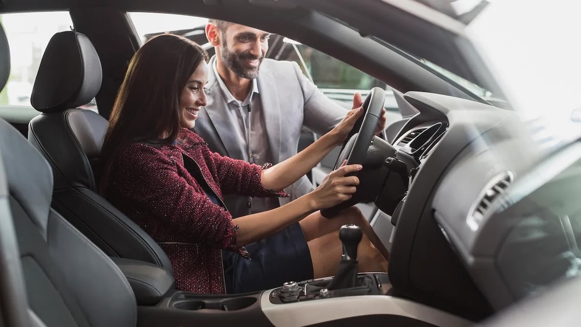 woman inspecting a new car at dealership
