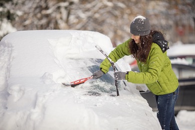 woman clearing snow off of car