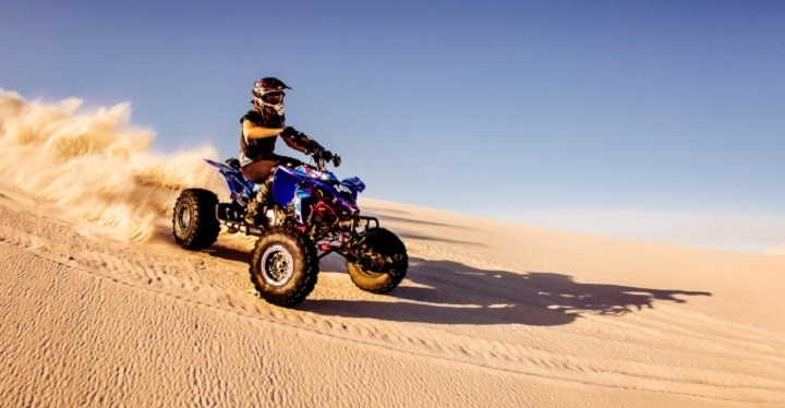 ATV driver riding down a sand dune