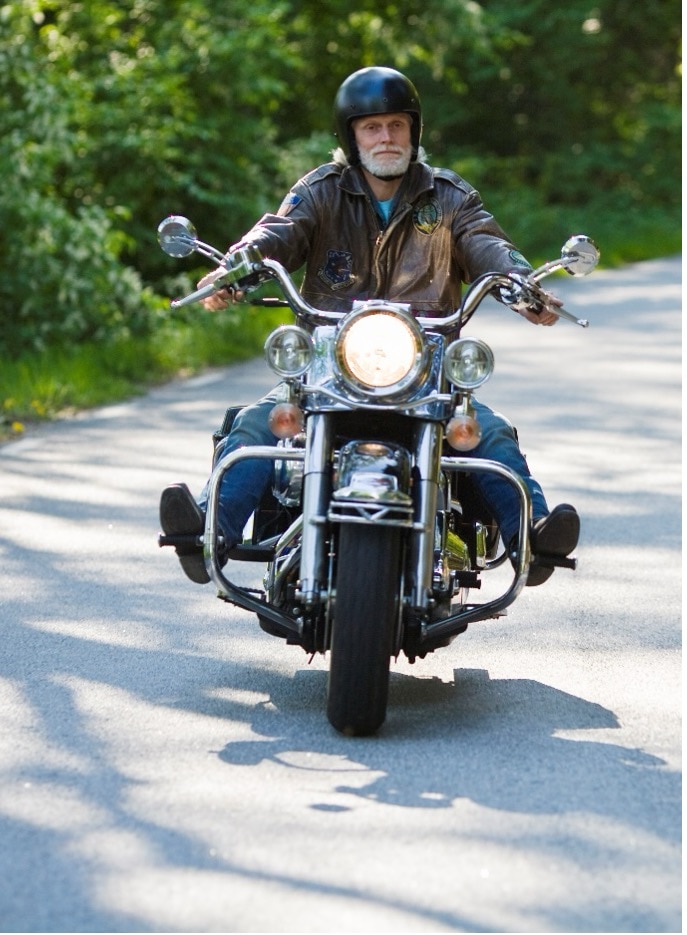 Man riding motorcycle on road with trees in background