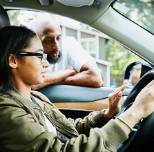 Father leaning in window talking to daughter in driver seat