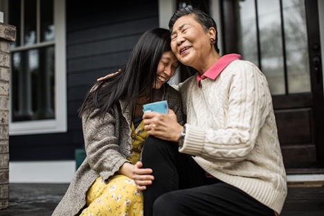 older mother and daughter laughing on porch