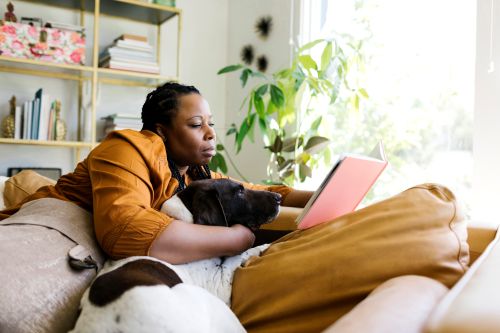 Woman with her dog reading a book on a couch