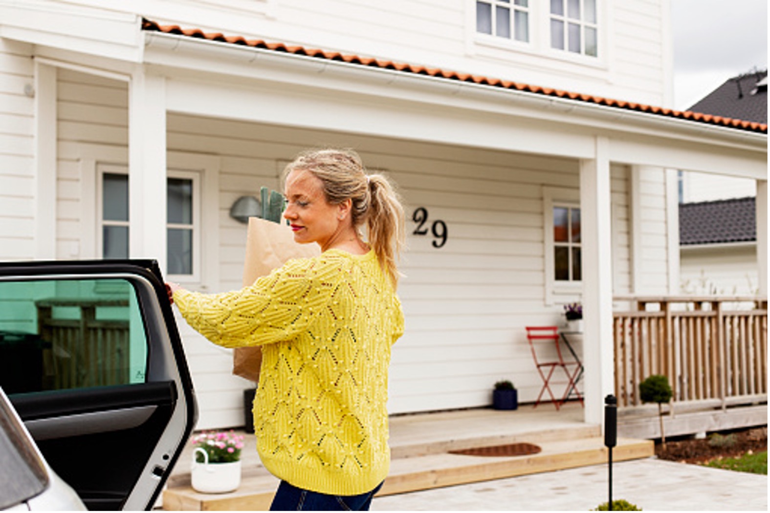 woman closing car door in front of a house