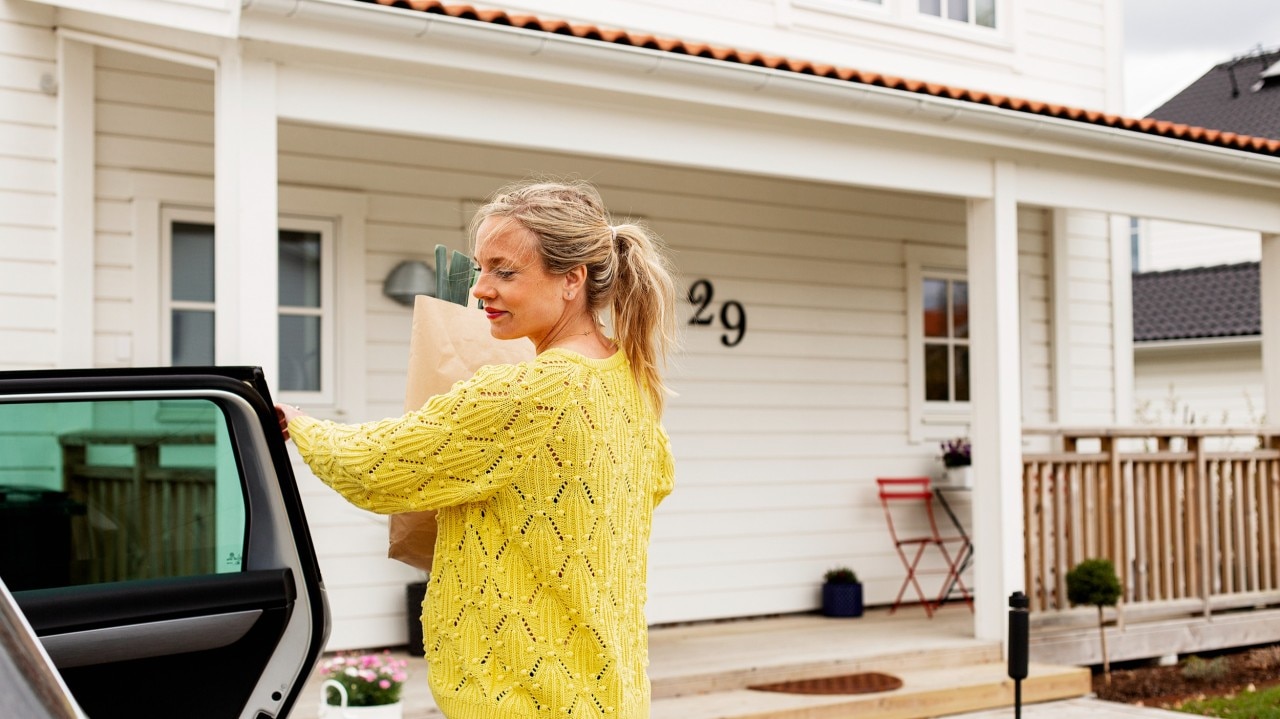 woman closing car door in front of a house