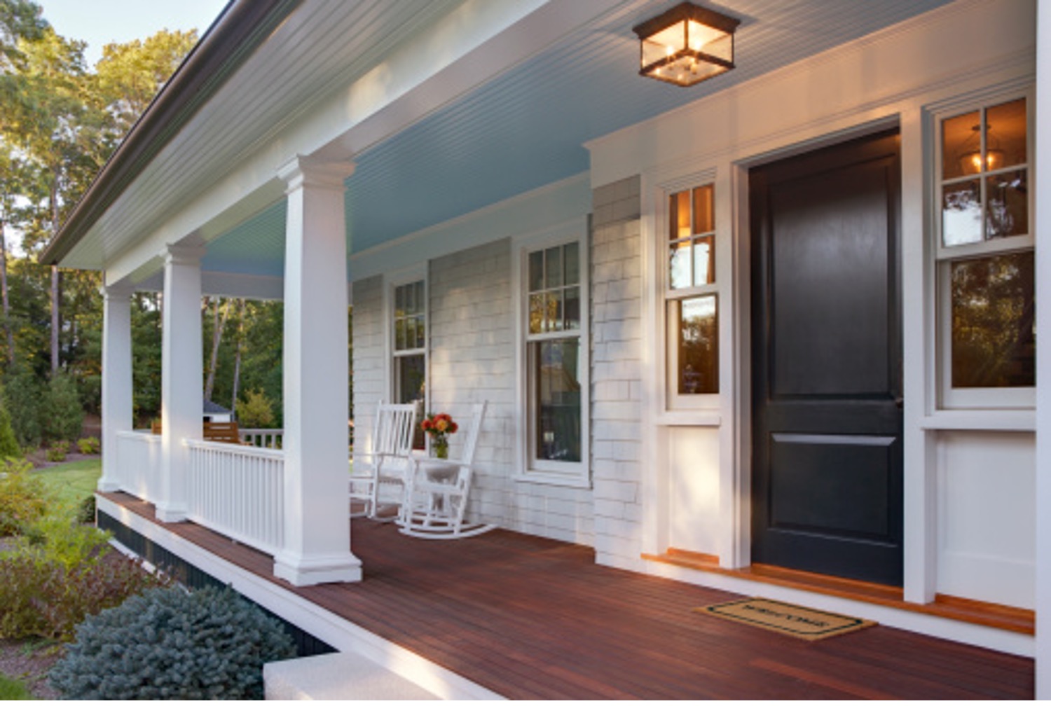 front door view of a white house with a wrap around porch