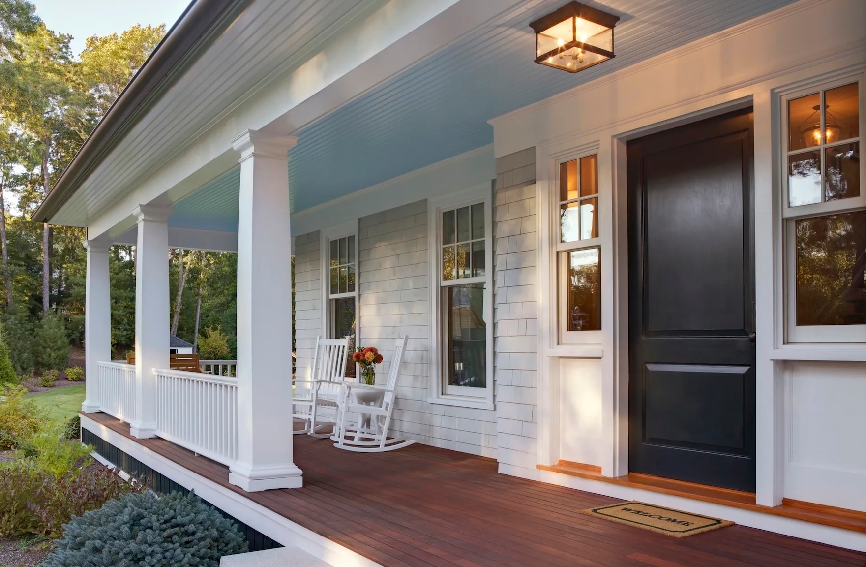 front door view of a white house with a wrap around porch