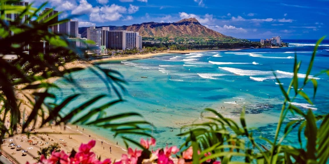 View of a beach in Hawaii with buildings and Mountains in the background