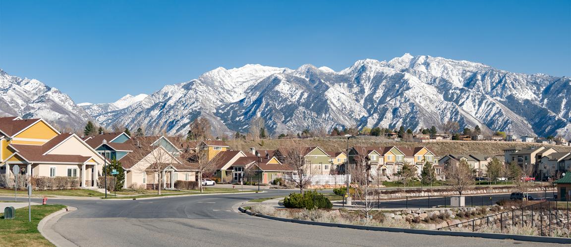 Suburban Utah neighborhood with snow covered rocky mountains in the distance.