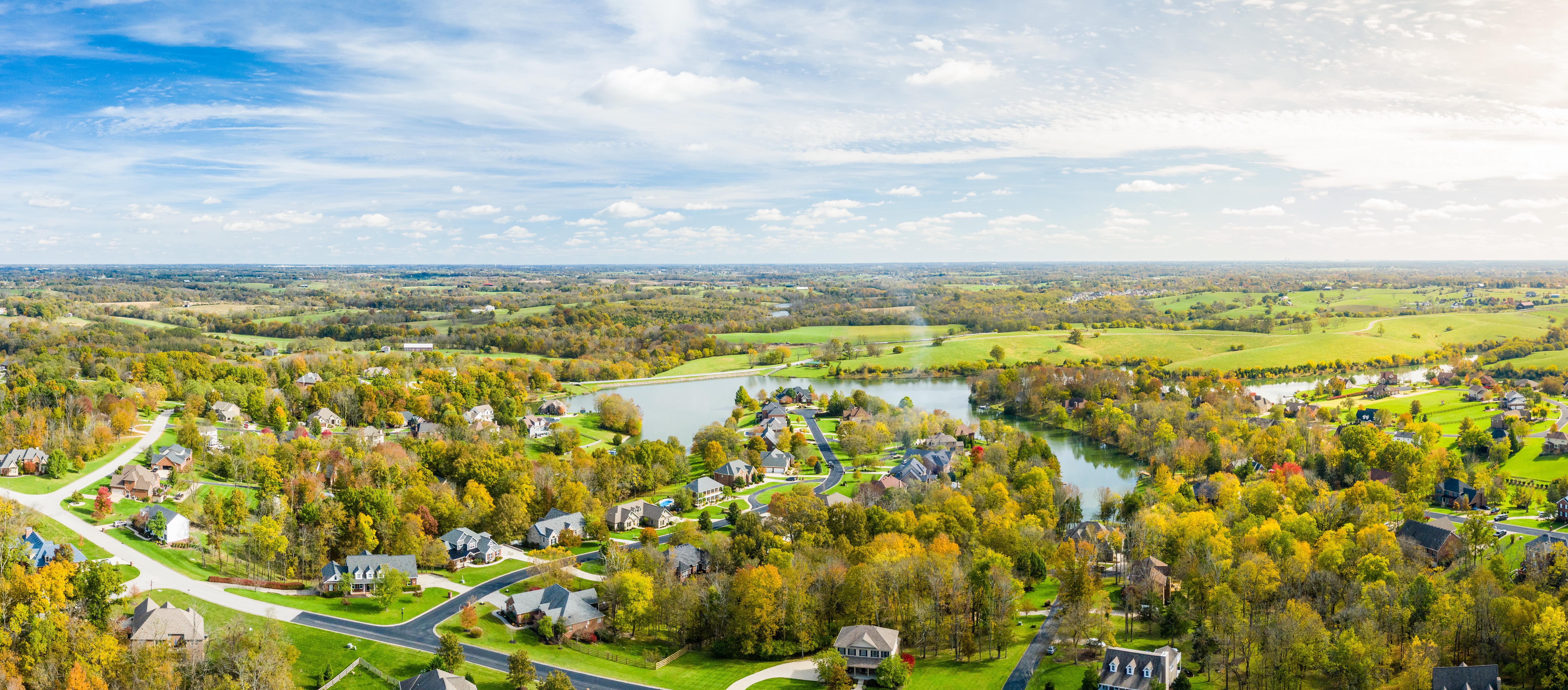 View of suburban neighborhood surrounded by trees and open fields