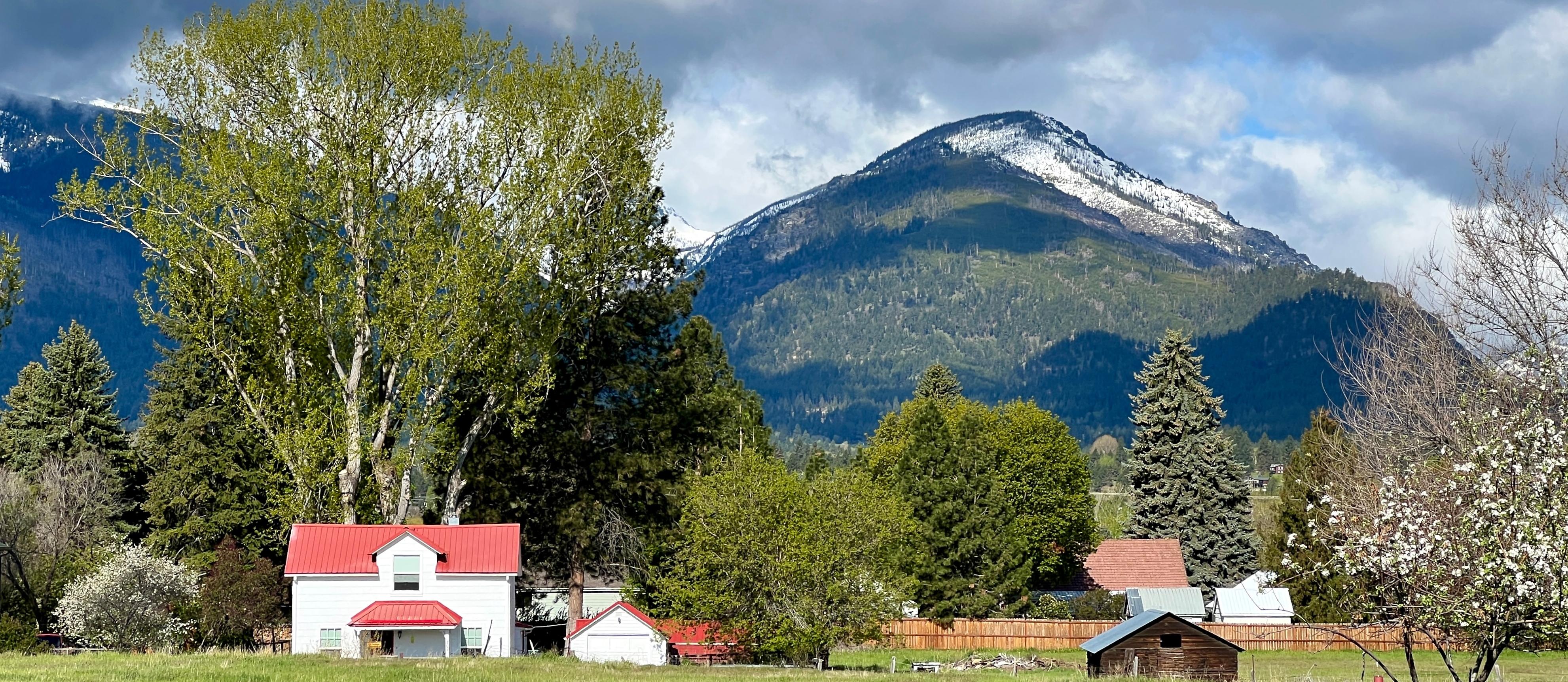 White house with red roof with view of trees and mountains