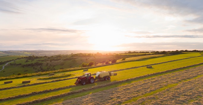 Red tractor baling hay in a rural Nebraska field