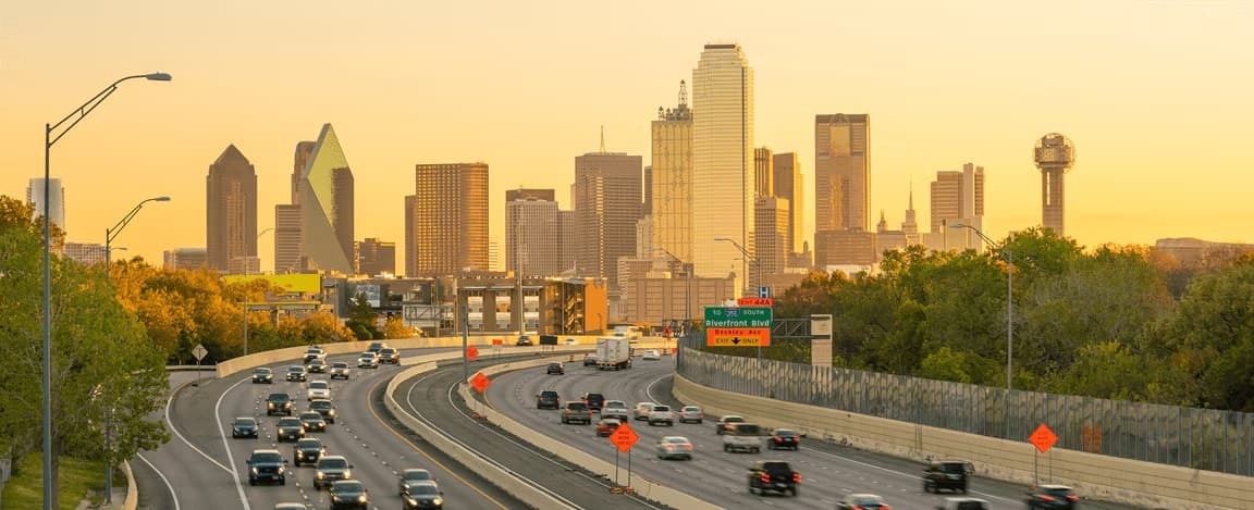 View of the Dallas, Texas skyline with insured cars driving on a highway.