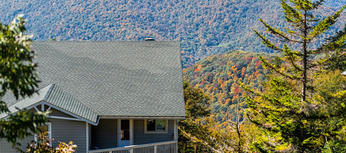 Gray house with fall colored trees on the mountain