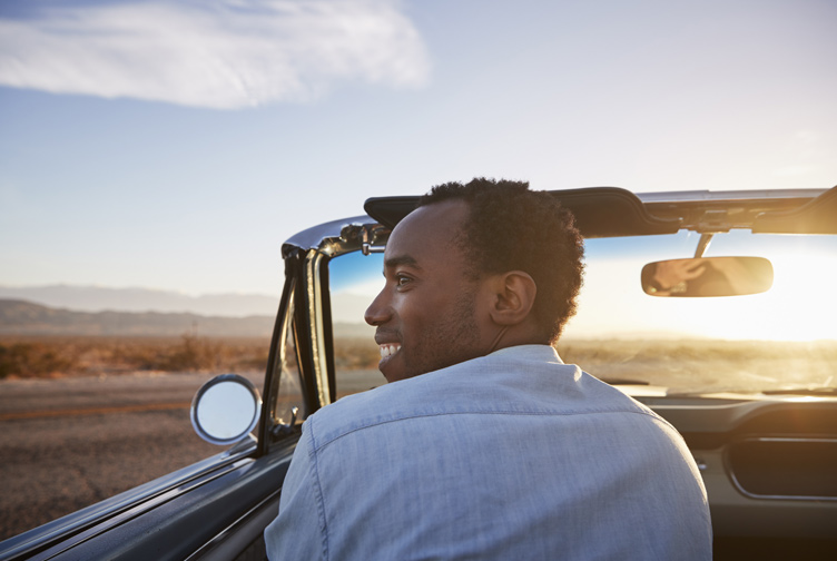 Man in a convertible enjoying a sunset drive.