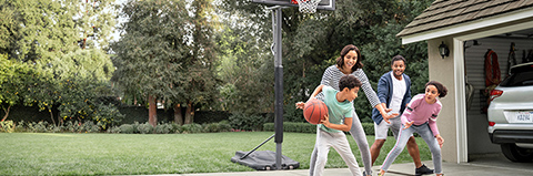 Family plays basketball in their driveway.