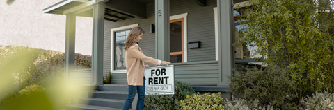Woman places "For Rent" sign on her front lawn.