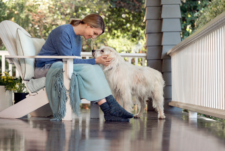 Woman pets her dog on her porch.