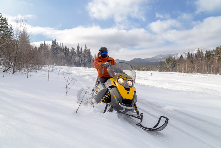 Snowmobile rider on a scenic snow trail.