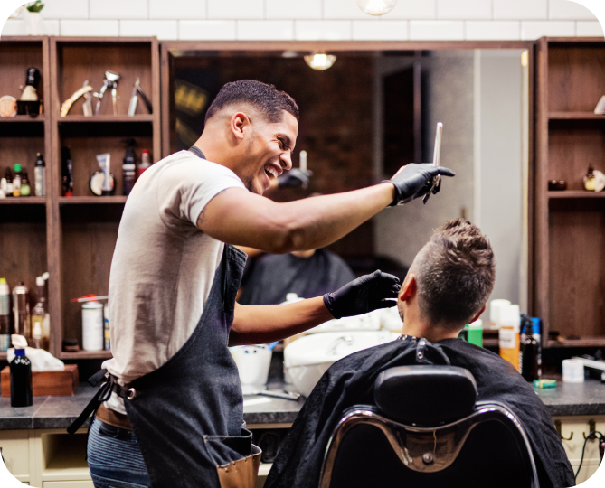 A barber wearing an apron and holding scissors giving a man a haircut.