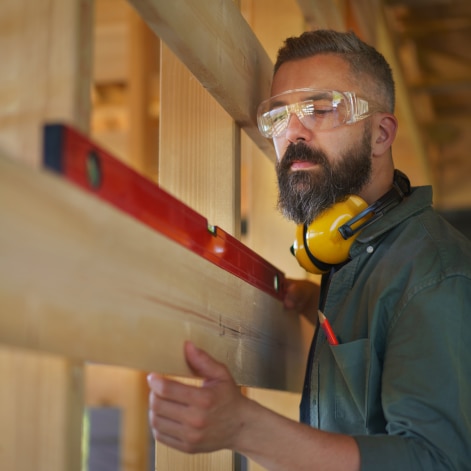 A man wearing protective goggles using a level at a construction site.