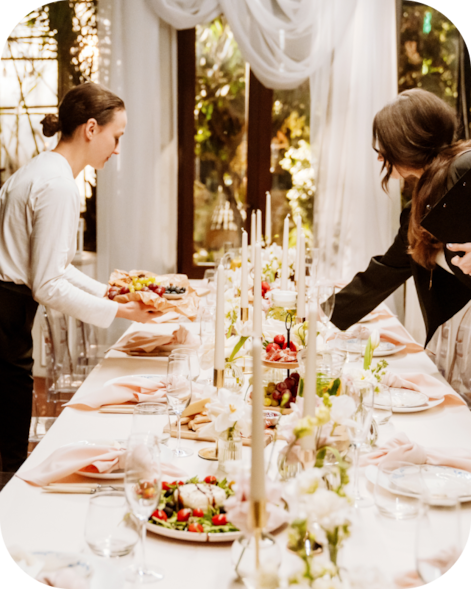 Server placing food on a decorated event table while a guest serves themselves.