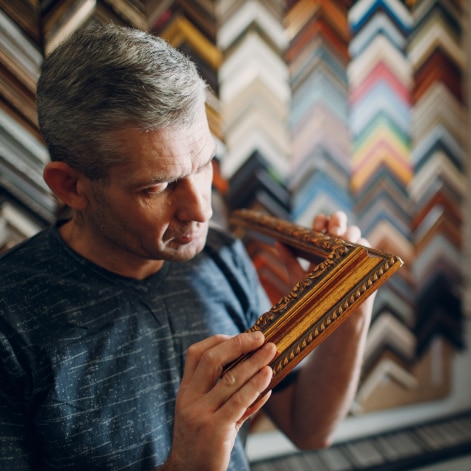 A Man holding a piece of a gold picture frame.