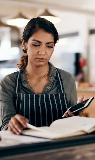 A Woman wearing an apron while holding a phone.