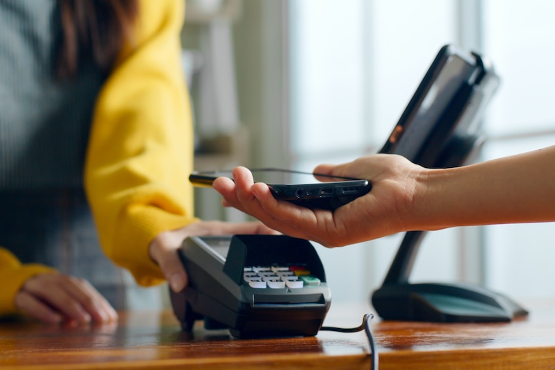 A hand holding a phone over a credit card reader.