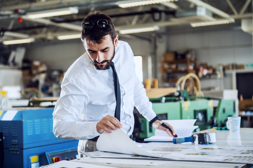 A man standing at a desk looking at blueprints.